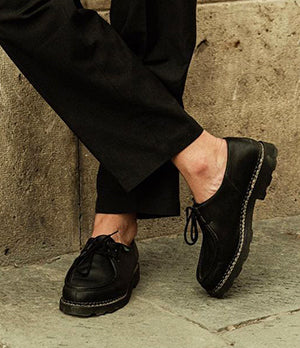 Close-up of Paraboot leather shoes styled with tailored trousers, showcasing handcrafted quality and timeless French design.